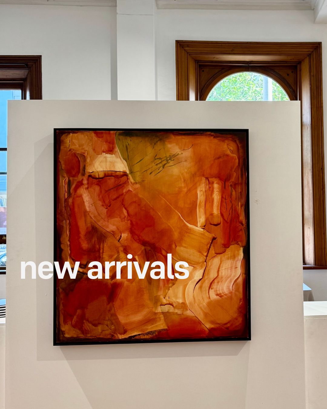 Abstract painting with 'new arrivals' text in a gallery setting